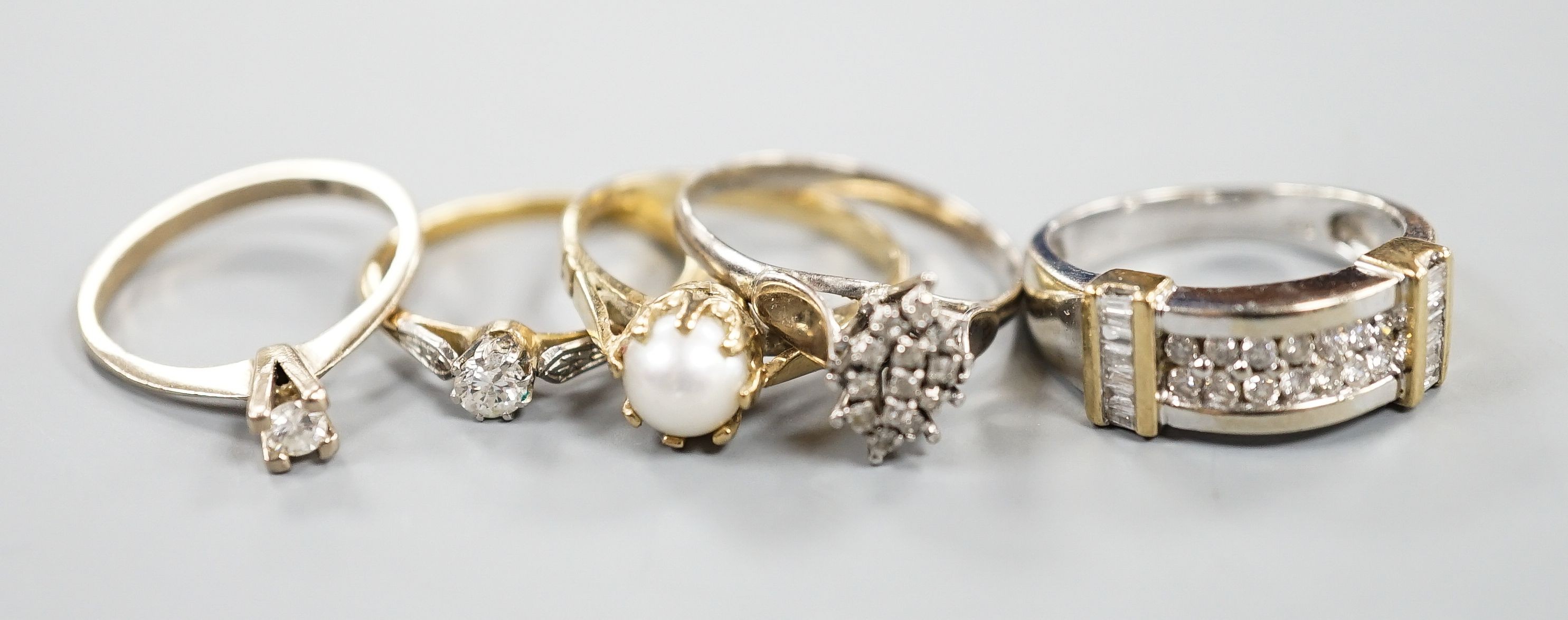 A 750 white metal and solitaire diamond ring, size K, gross 2 grams, two other yellow or white metal diamond set rings, gross 3.4 grams and two 9ct and gem set rings including cultured pearl, gross 6.3 grams.